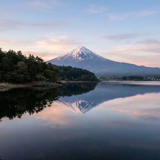 Perfect mirror reflection of Mount Fuji in the still waters of Lake Kawaguchiko at dawn, seen from Ubuyagasaki Peninsula